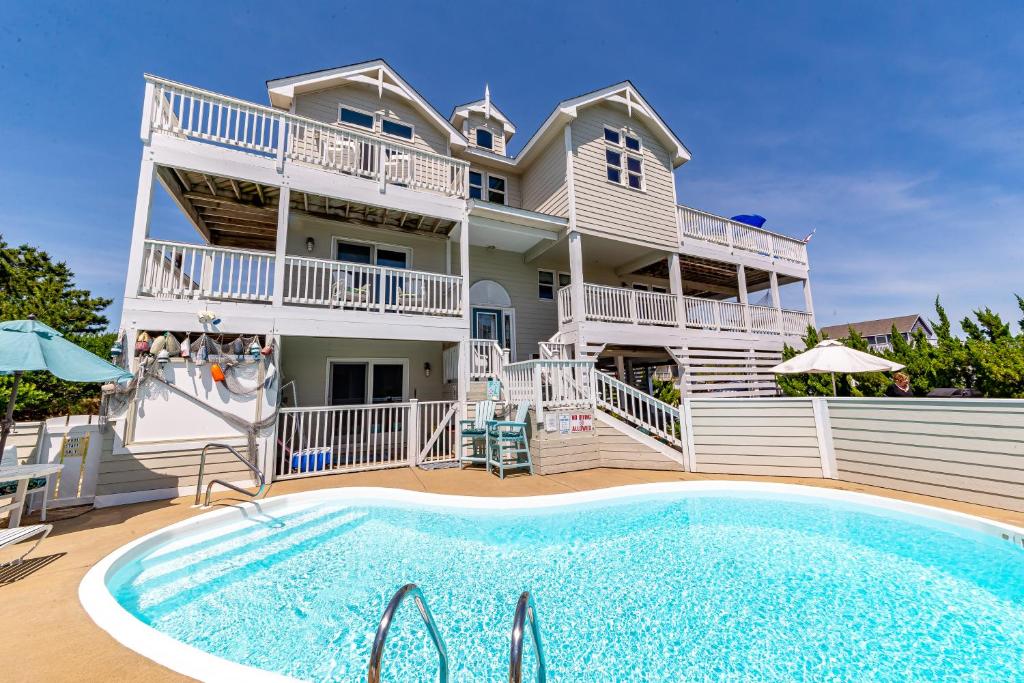 a large house with a swimming pool in front of it at Simple Gifts by the Sea in Duck