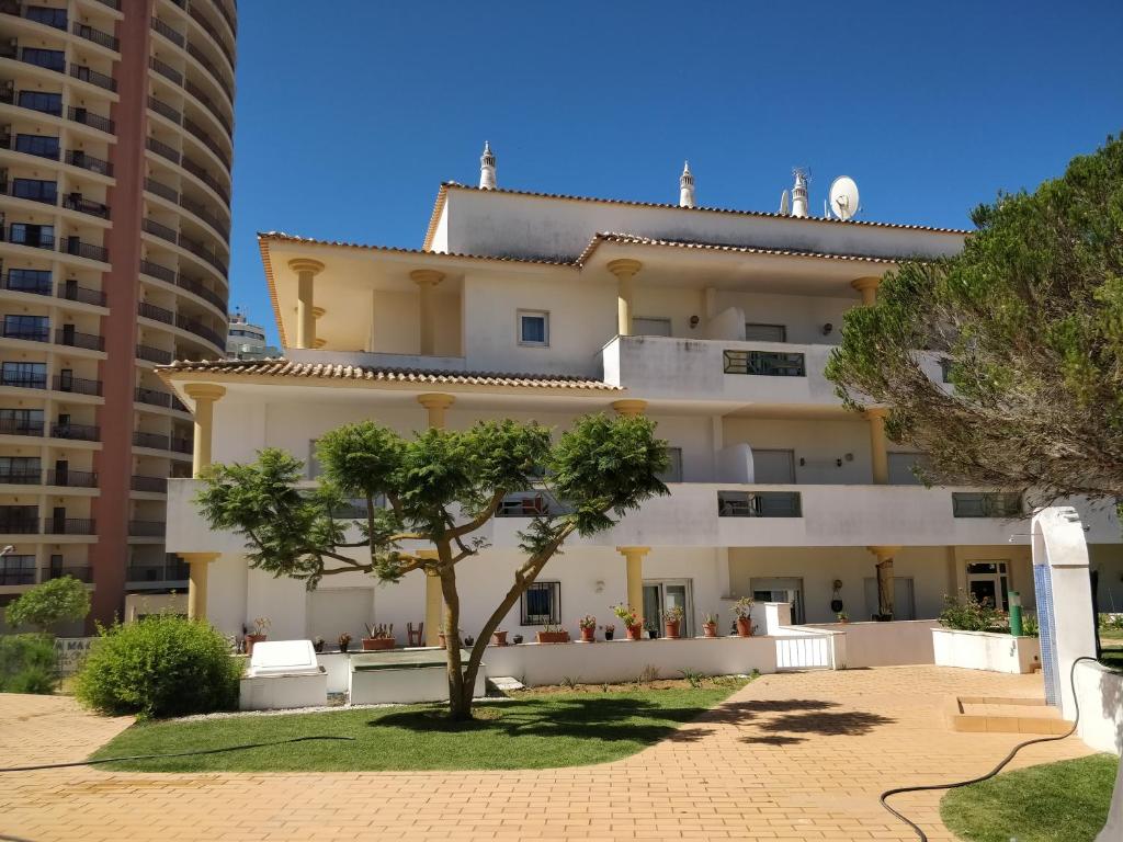 a building with a tree and two tall buildings at Primavera in Portimão