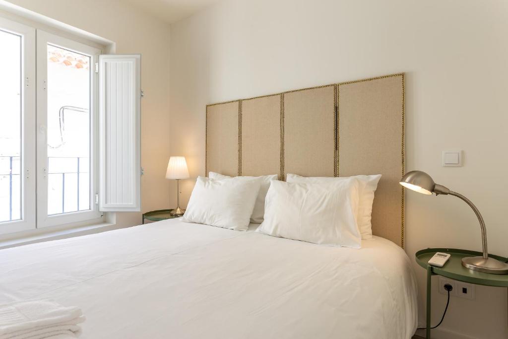 - une chambre dotée d'un grand lit avec des draps et des oreillers blancs dans l'établissement Apartment Martim Moniz - Tram 28, à Lisbonne
