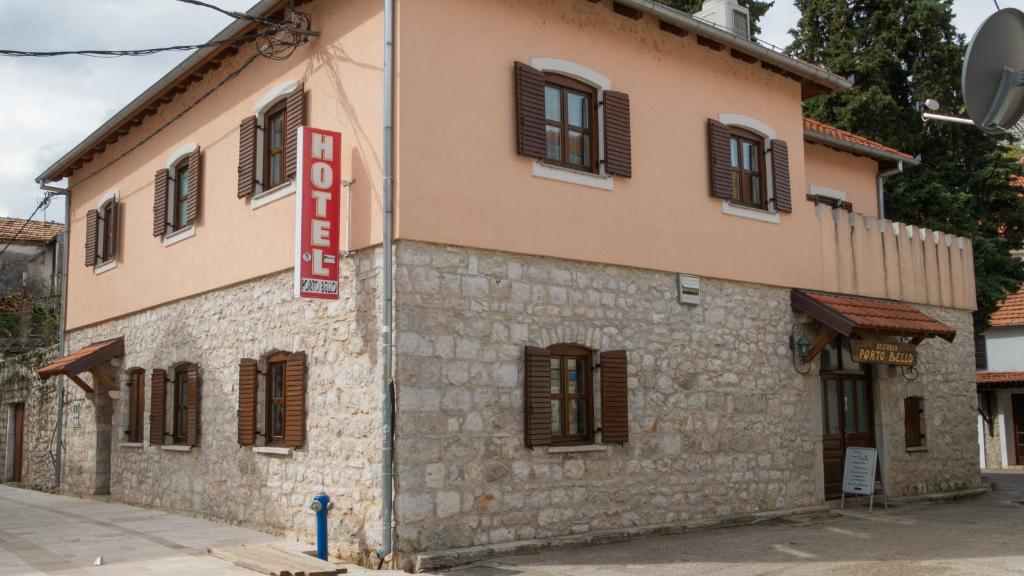 a building with a red sign on the side of it at Hotel Porto Bello in Trebinje