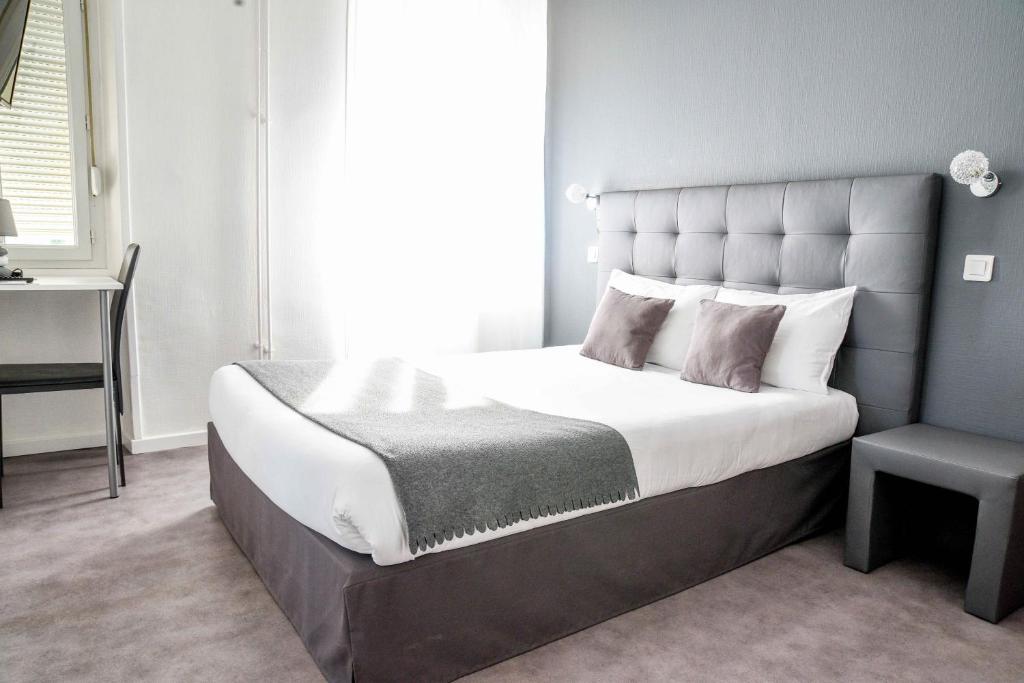 1 dormitorio con 1 cama grande y 1 silla en Hotel l'Europe - Cholet Gare, en Cholet