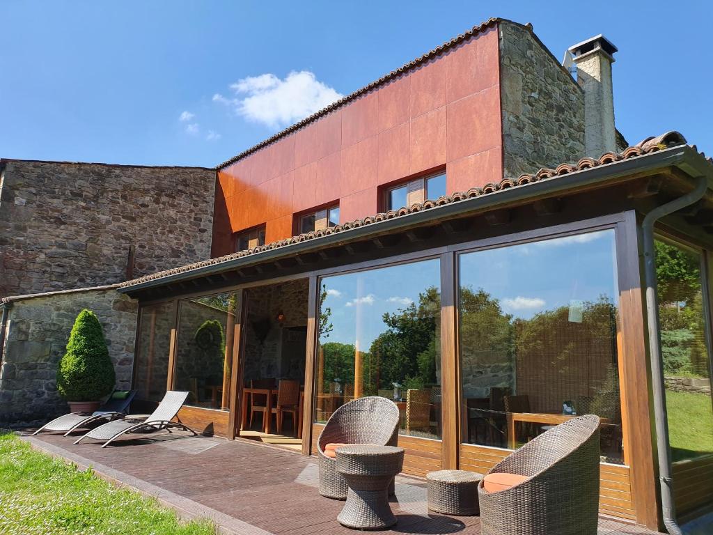 a house with glass doors and chairs on a patio at Rectoral De Lestedo in Palas de Rei