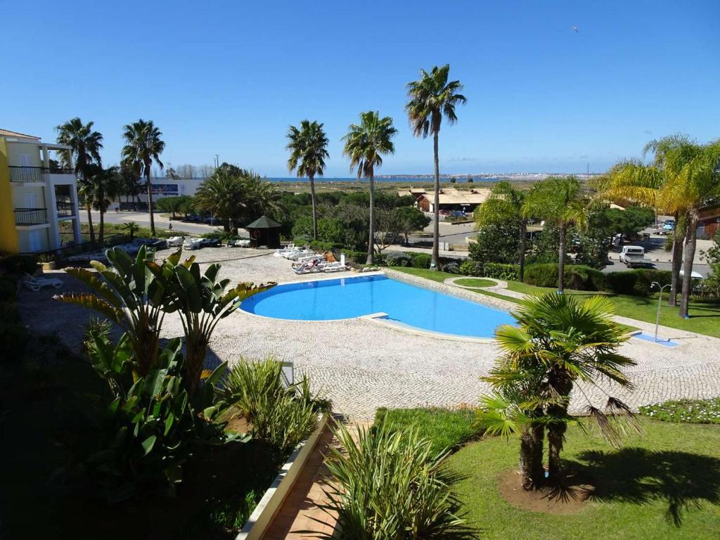 einen Pool in einem Resort mit Palmen in der Unterkunft One Bedroom Apartment with Stunning Views in Alvor