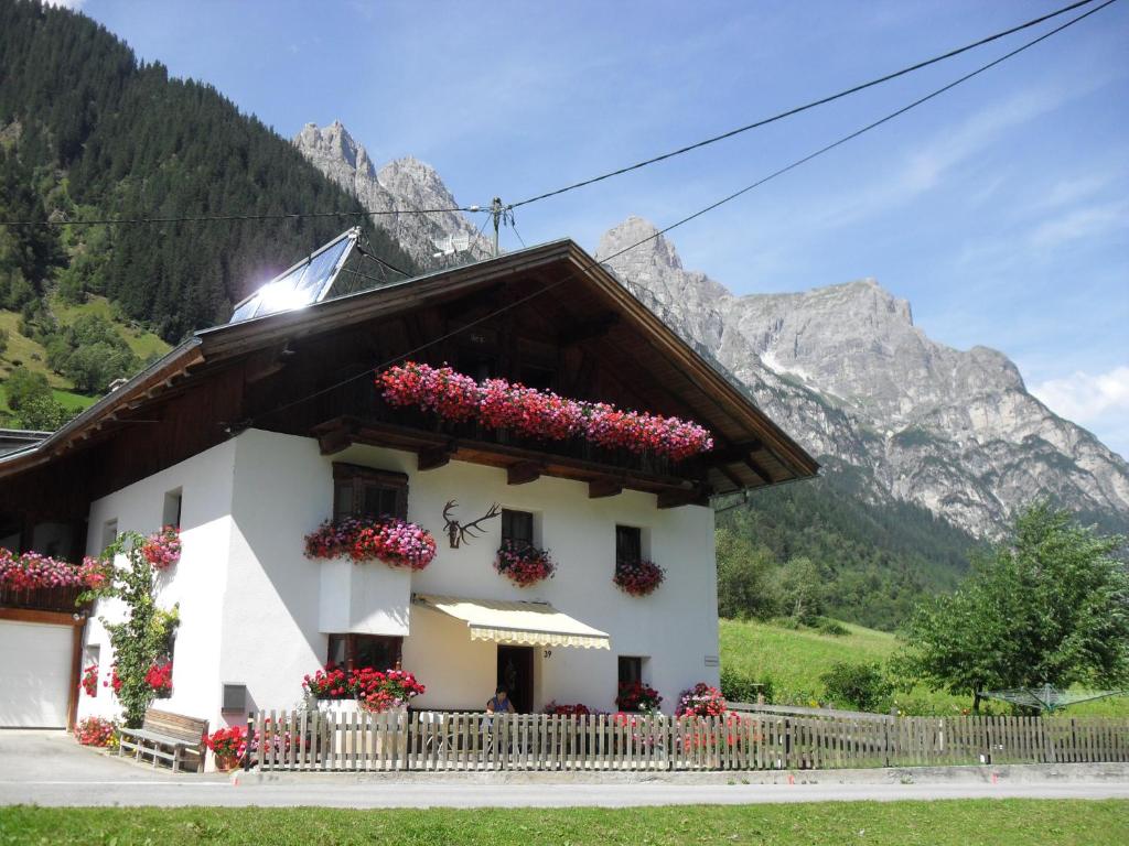 ein weißes Haus mit Blumen vor einem Berg in der Unterkunft Pirschenhof in Gschnitz