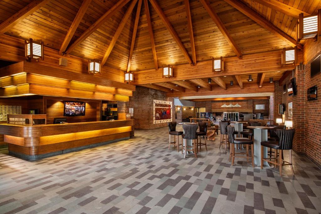 um restaurante com tectos e mesas e cadeiras de madeira em Valhalla Hotel & Conference Centre em Thunder Bay