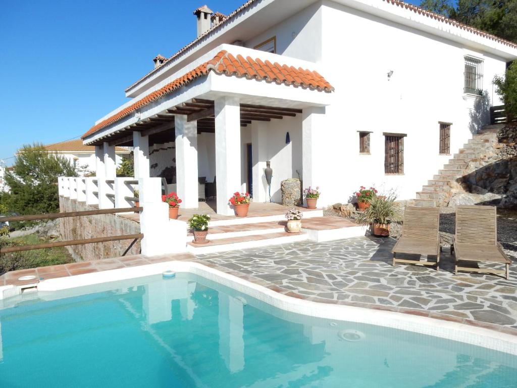 a villa with a swimming pool in front of a house at Casa del Limonero in Guaro