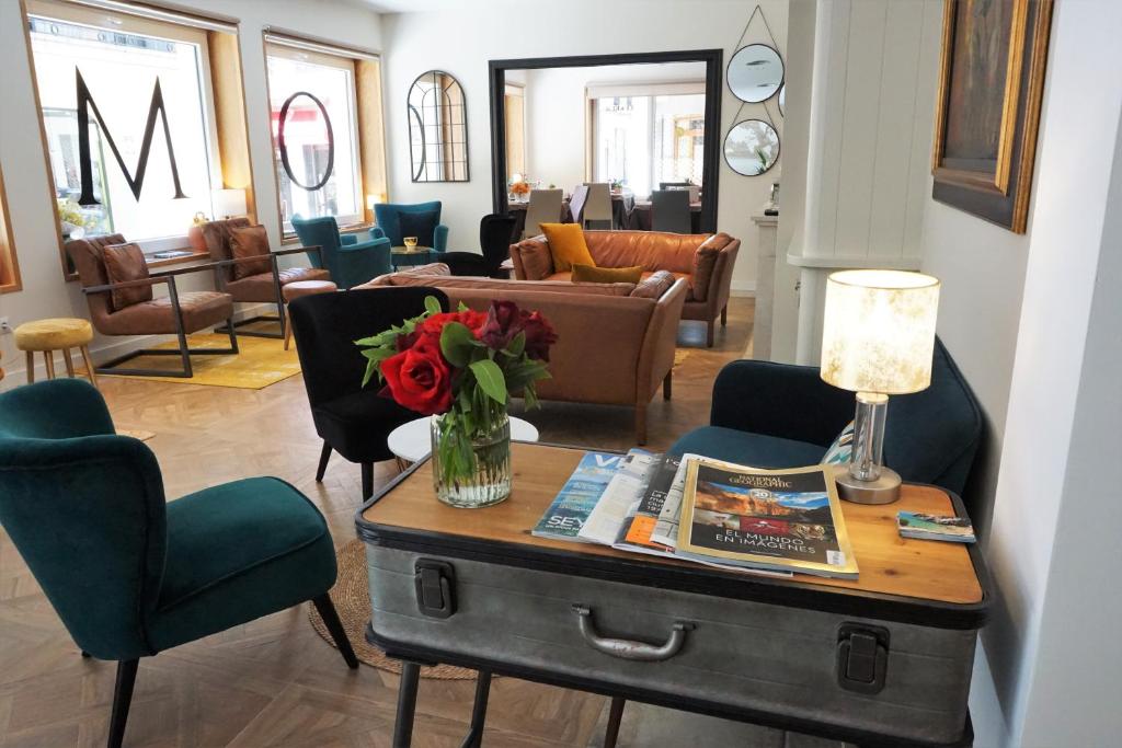 a living room with a table with a vase of flowers at Hotel Boutique OMA in Sant Feliu de Guixols