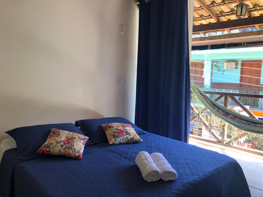 Una cama con dos toallas junto a una ventana. en Pousada Porto do Sol en Ilha Grande