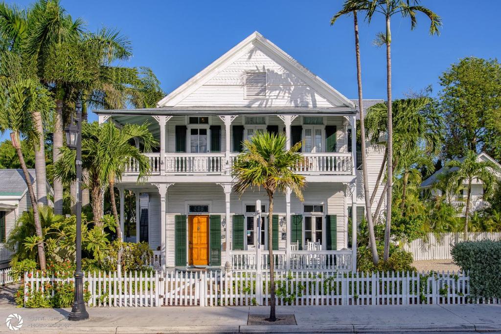 una casa blanca con una valla blanca y palmeras en The Conch House Heritage Inn, en Key West