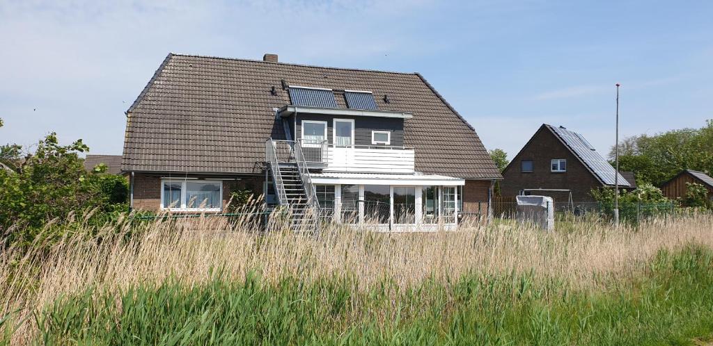 una casa en un campo de hierba alta en Ferienwohnungen Haus Schau ins Land nah an der Nordsee, en Emmelsbüll-Horsbüll