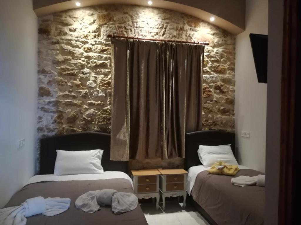 two beds in a room with a stone wall at Skourtaniotis spa rooms in Loutra Edipsou