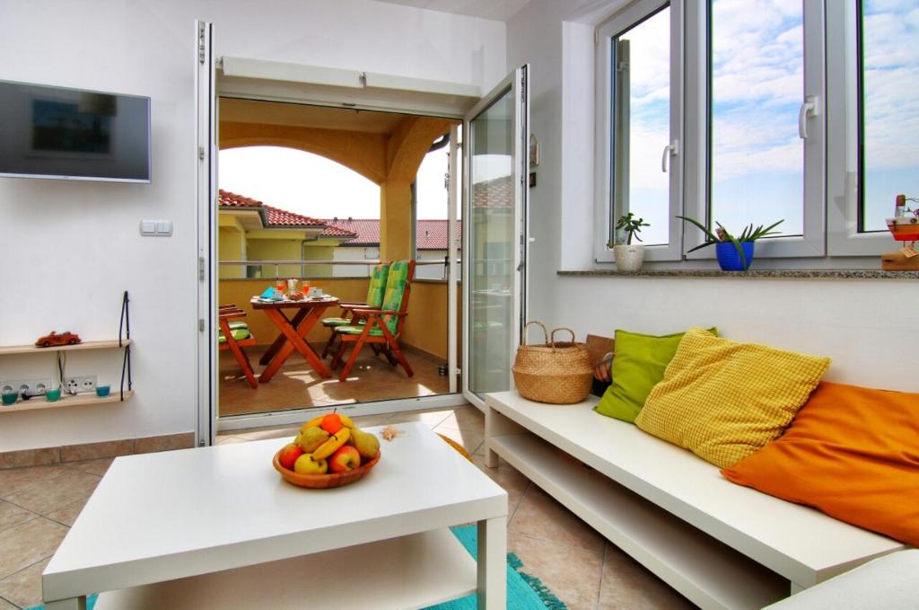 een kamer met een bank en een tafel met een fruitschaal bij Apartman Eli Smokvica in Klenovica