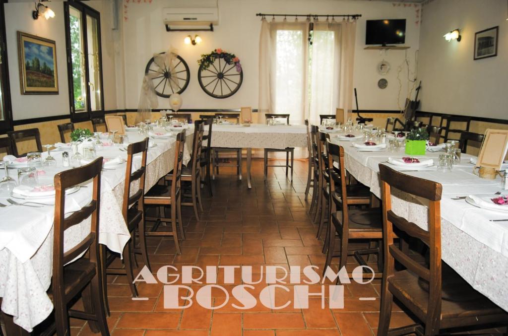 una sala da pranzo con tavoli e sedie bianchi di Agriturismo Boschi a Reggiolo