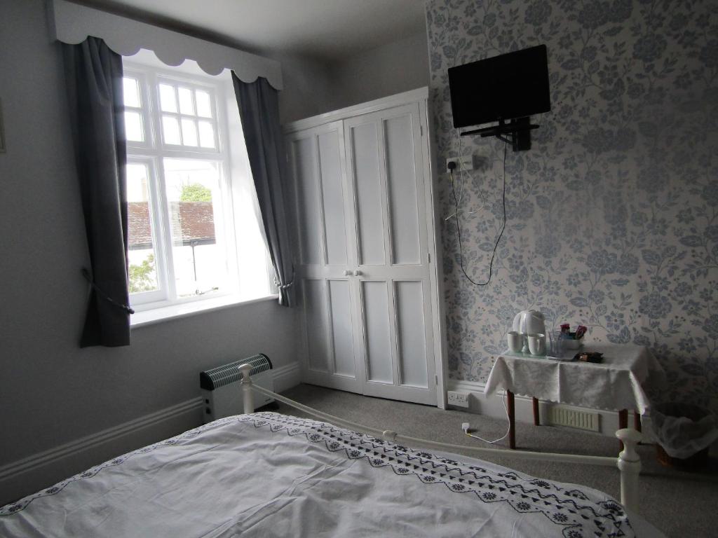1 dormitorio con cama, ventana y lavamanos en The Old Post House, en Moretonhampstead