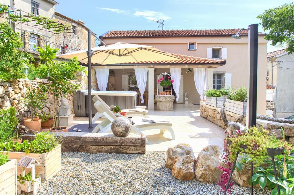 a patio with an umbrella and some plants at White Cottage Heritage House in Čižići