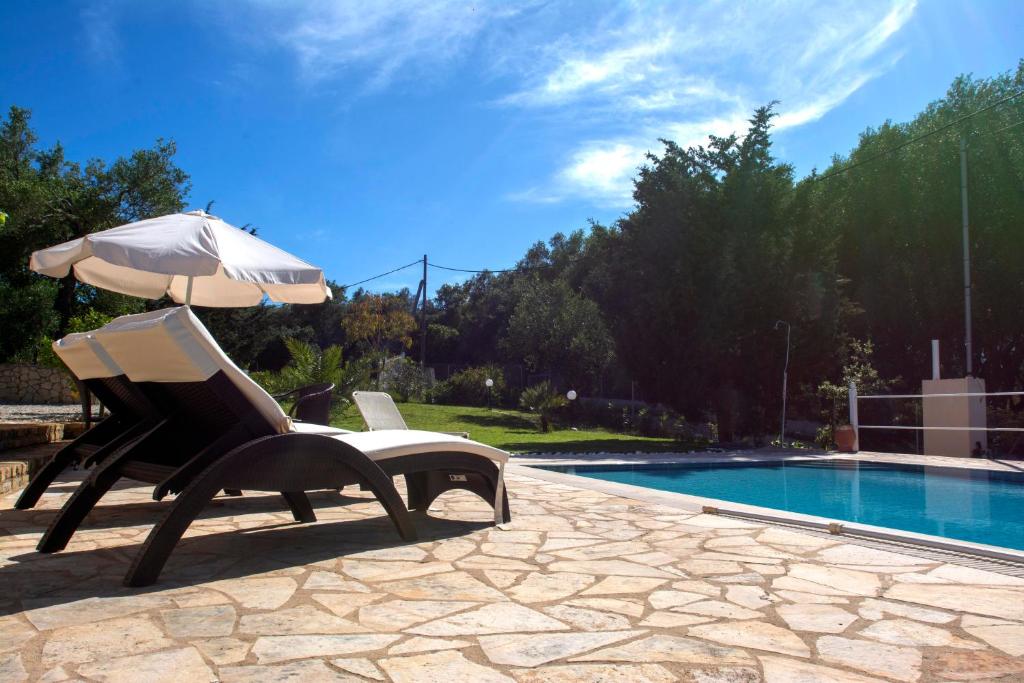 a chair and an umbrella next to a swimming pool at Oleander villa in Kouramaditika