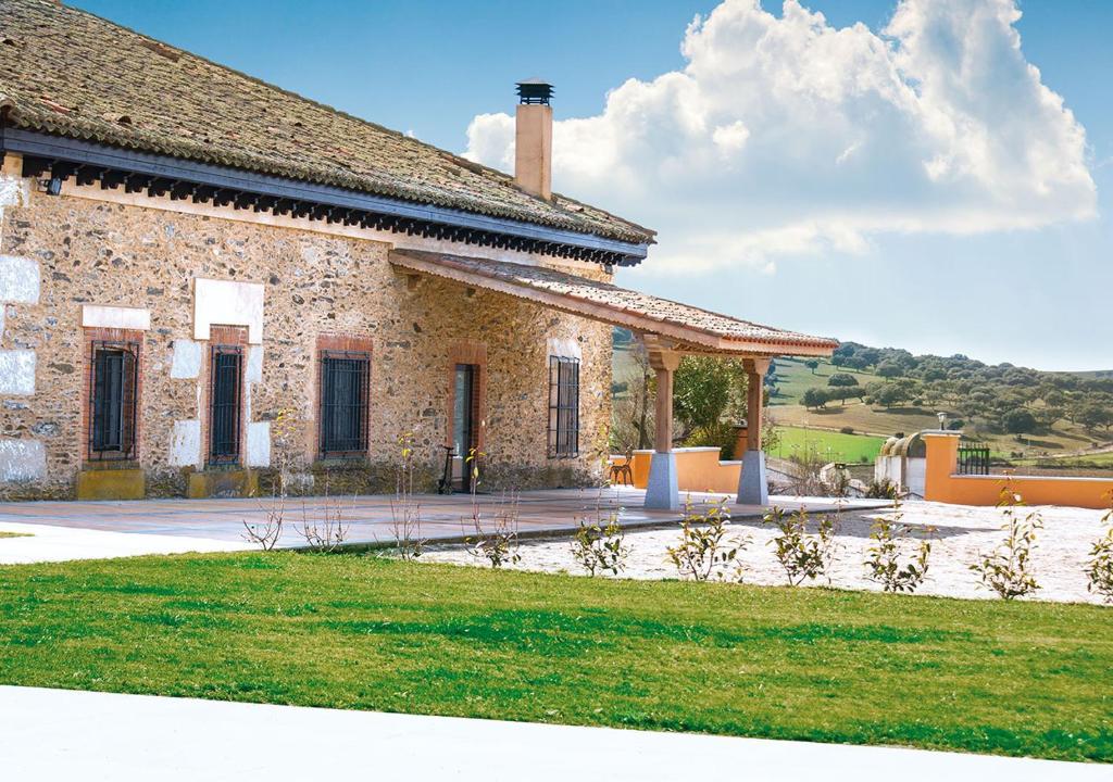 un bâtiment en briques avec une cour herbeuse devant lui dans l'établissement Casa Rural La Torrecilla, à San Pedro del Valle