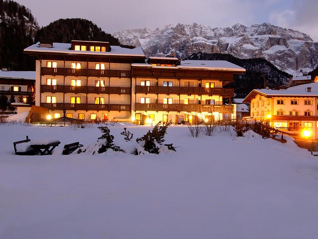 un bâtiment dans la neige la nuit avec de la neige dans l'établissement Hotel Antares, à Selva di Val Gardena