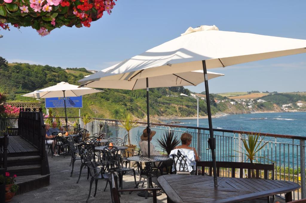 two people sitting at tables under an umbrella at The Hannafore Point Hotel in Looe