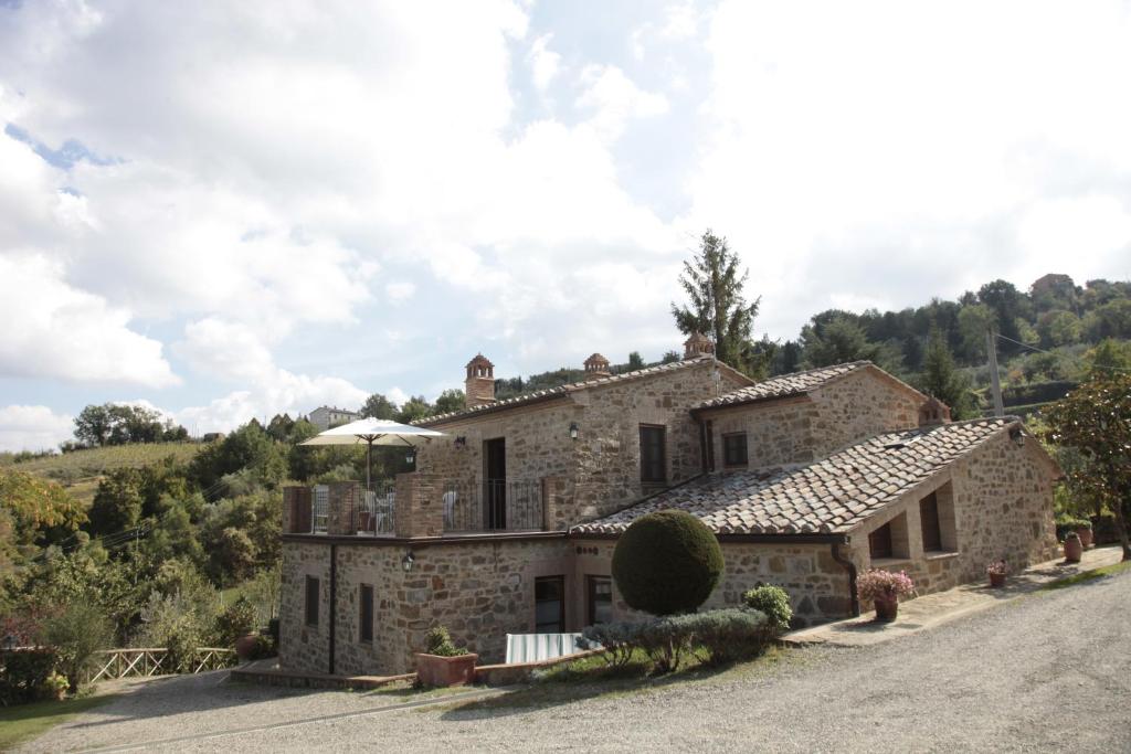 una vecchia casa in pietra su una collina con vialetto di Azienda Agraria La Casella a Montalcino