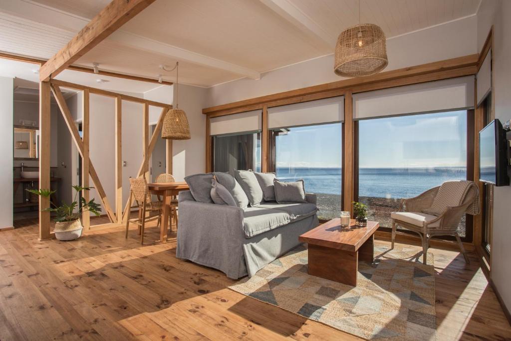 a living room with a couch and a view of the ocean at Cala Melí in Puerto Varas