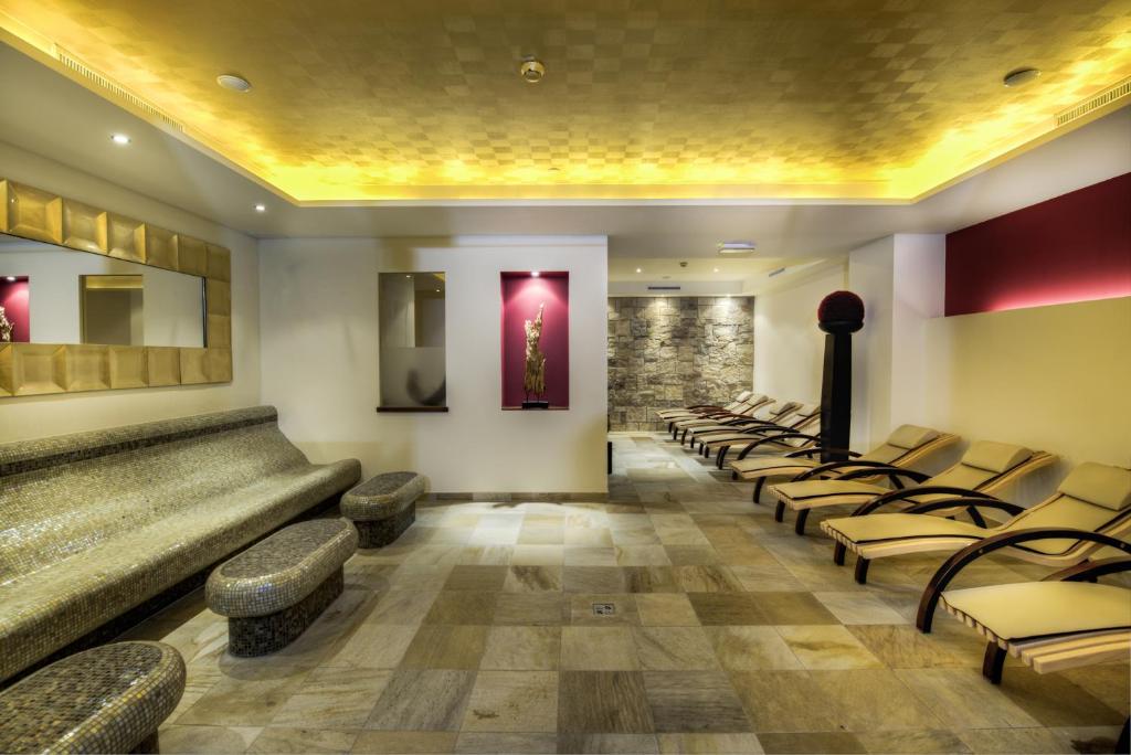 a waiting room with a row of chairs and a stone wall at Hotel Brigitte in Ischgl