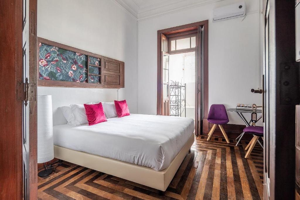 sypialnia z białym łóżkiem i różowymi poduszkami w obiekcie Urban Suites w mieście Aveiro