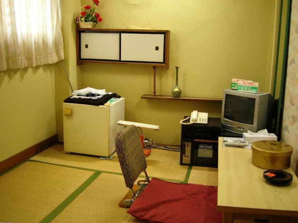 a room with a desk and a refrigerator and a tv at Komecho Ryokan / Vacation STAY 33206 in Imabari