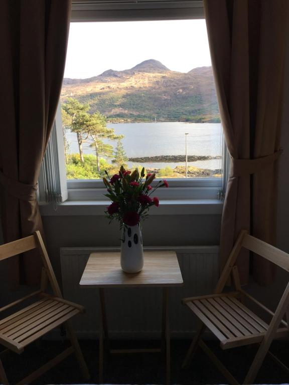 a vase of flowers sitting on a table in front of a window at Lochalsh View, Kyle, 1 Mile to Skye in Kyle of Lochalsh