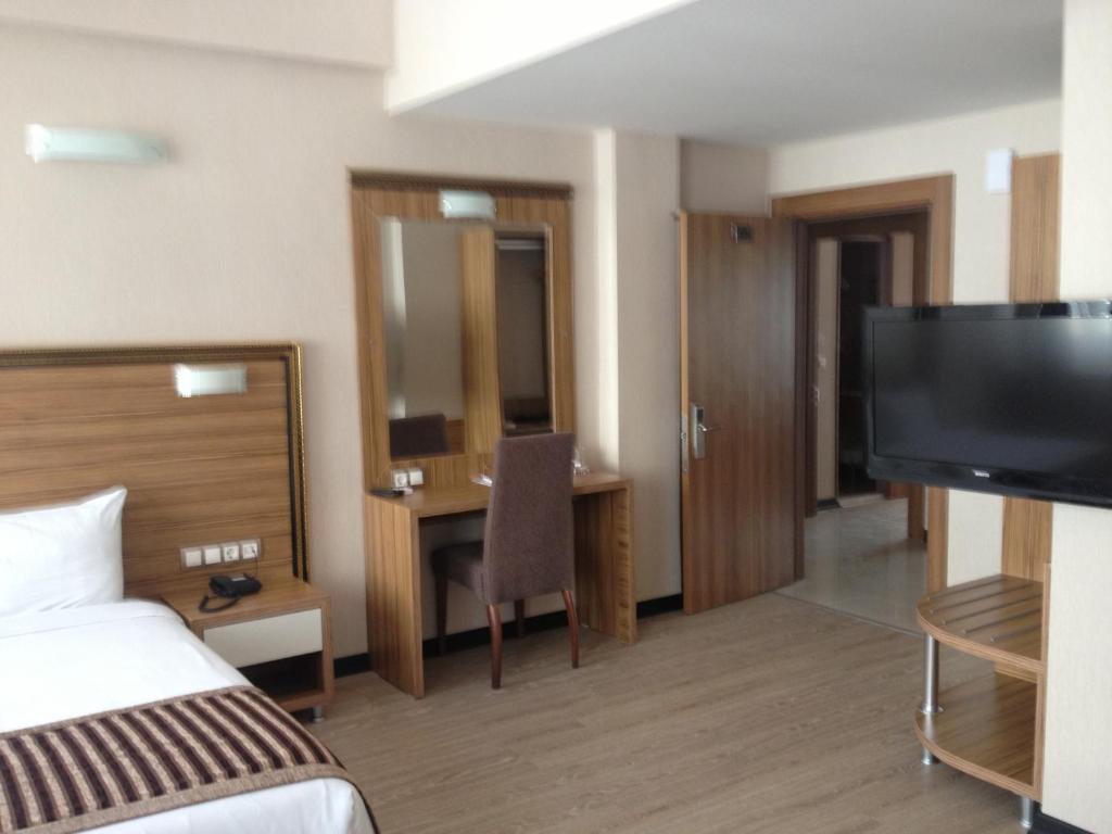 ein Hotelzimmer mit einem Bett und einem Flachbild-TV in der Unterkunft Buyuk Hotel in Kayseri