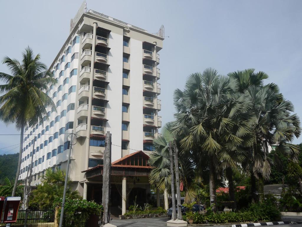 een hoog gebouw met palmbomen ervoor bij Eagle Bay Hotel in Kuah