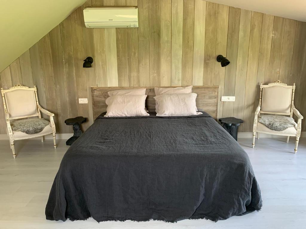 a bedroom with a large bed with two chairs at B&B Silentium in Tielt