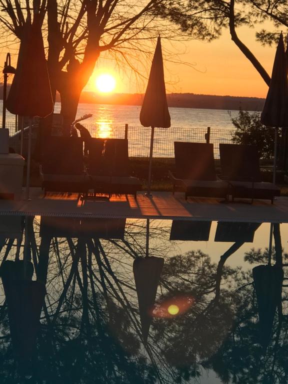 a reflection of the sunset in a pool with chairs and umbrellas at Residence Alexandra Stay in Sirmione