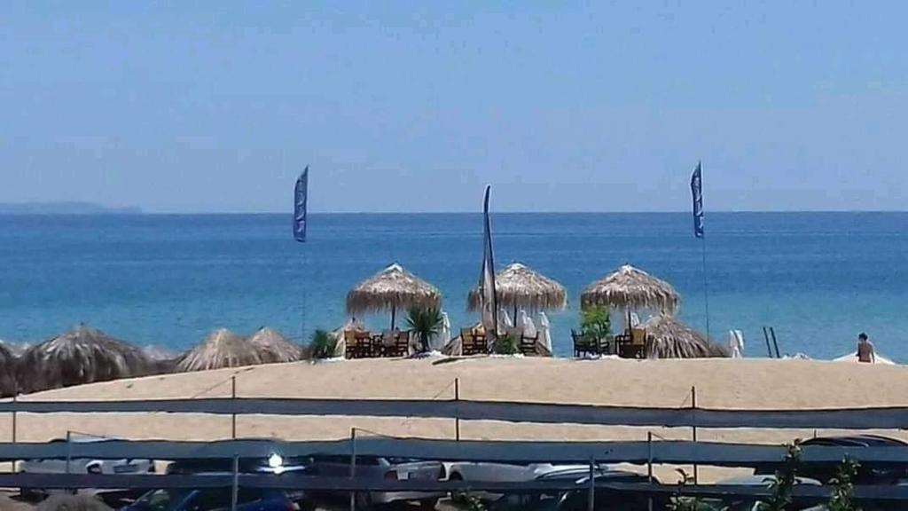 a beach with chairs and umbrellas and the ocean at Ammolofi Villas in Nea Peramos