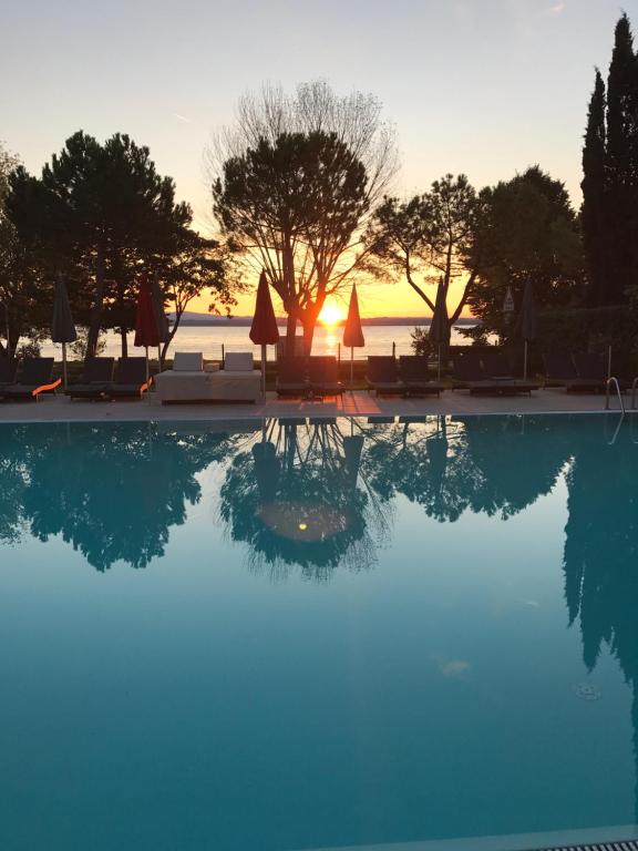 a swimming pool with a sunset in the background at Residence Alexandra Stay in Sirmione