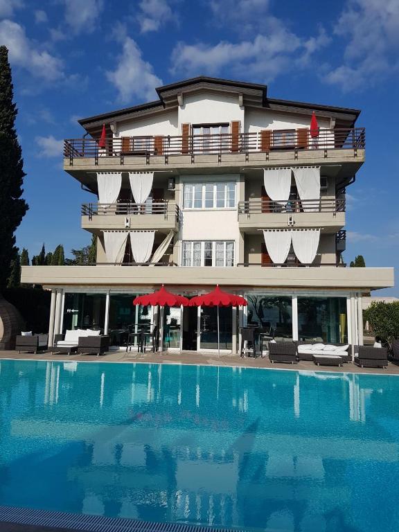 a hotel with a swimming pool in front of a building at Residence Alexandra Stay in Sirmione