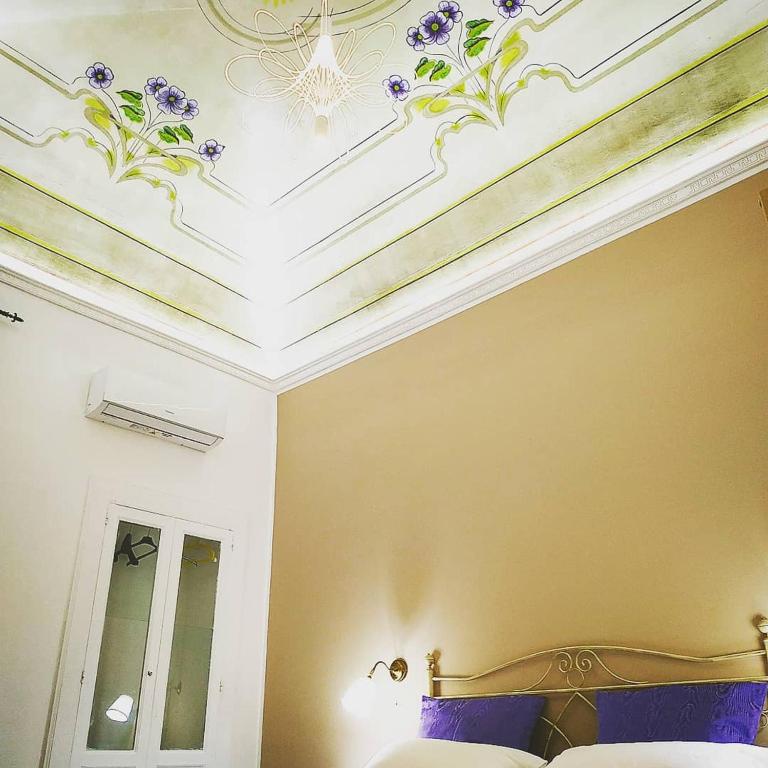 a bedroom with a bed and a ceiling with purple flowers at Le Suite del Teatro cucinino privato in Taranto