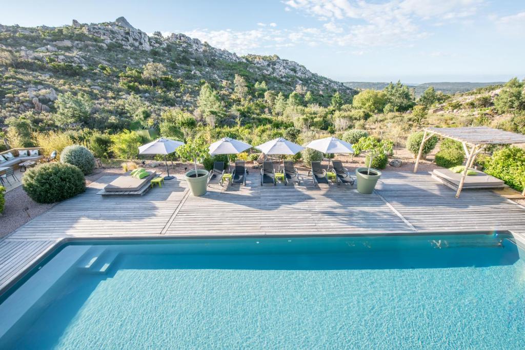 a pool with chairs and umbrellas on a deck at Hotel Les Chambres de Mila in Bonifacio