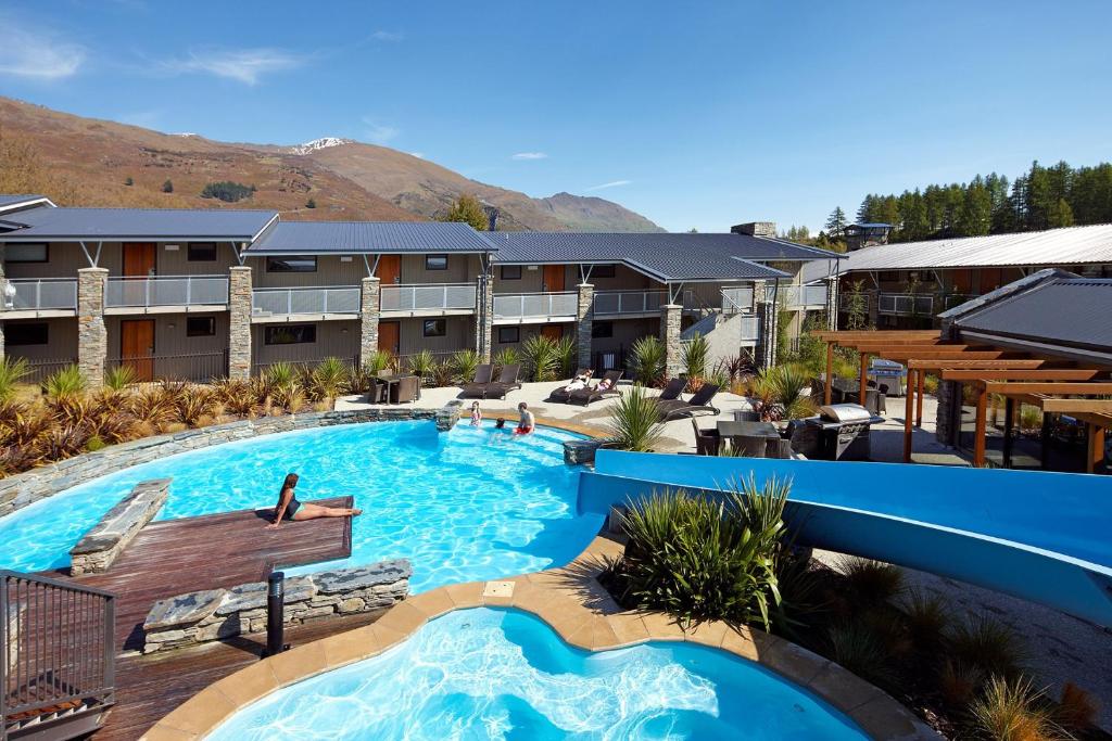 a large swimming pool in a resort with mountains in the background at Club Wyndham Wanaka, Trademark Collection by Wyndham in Wanaka