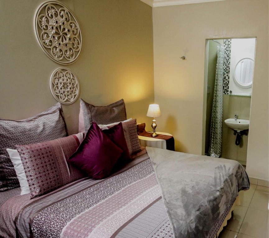 a bedroom with a bed with purple pillows and a sink at Patterson B&B in Newcastle