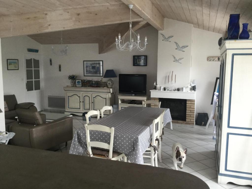 eine Küche und ein Wohnzimmer mit einem Tisch und einer Katze in der Unterkunft Maison de standing style rethais in Le Bois-Plage-en-Ré