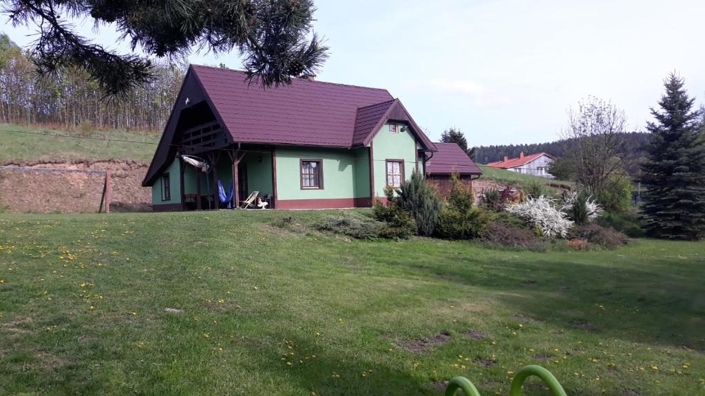Dach Pod Sową في لودفيكوفيتسا كواتسكي: منزل بسقف أرجواني على حقل أخضر