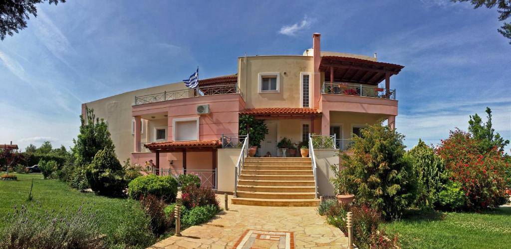 ein großes rosafarbenes Haus mit Treppe davor in der Unterkunft BRINA'S LUXURY APARTMENTS in Áyioi Apóstoloi