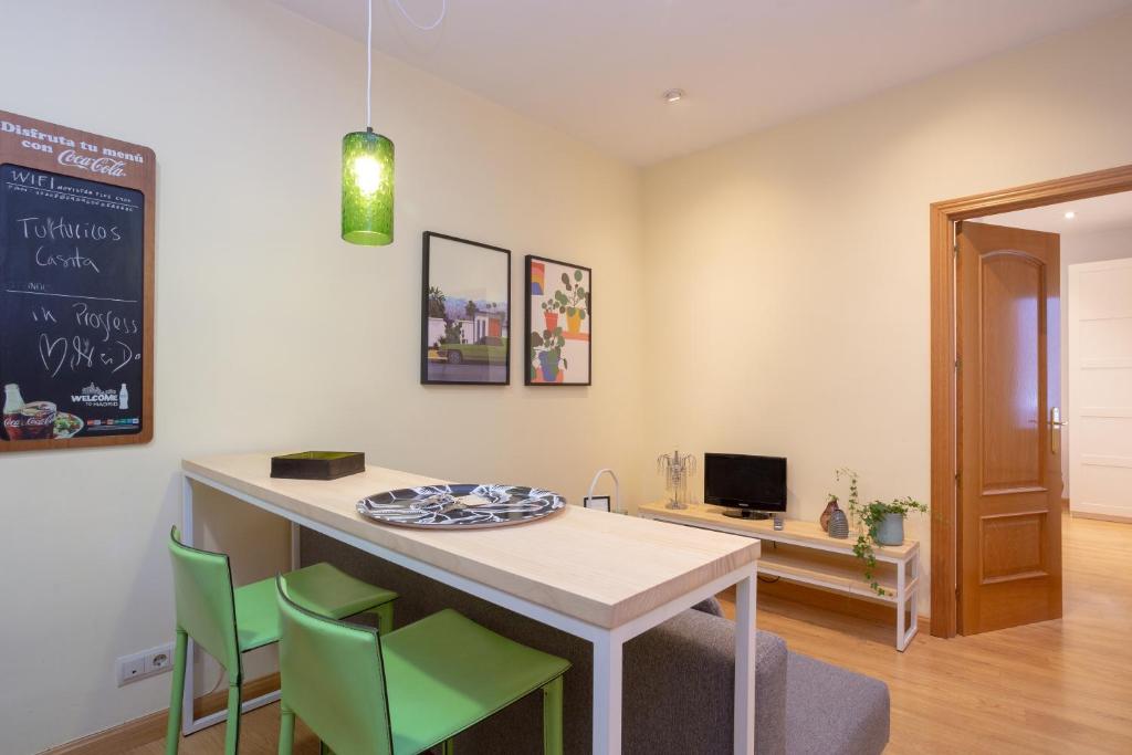 a kitchen with a table with green chairs and a chalkboard at Apartamentos Esperanza in Madrid