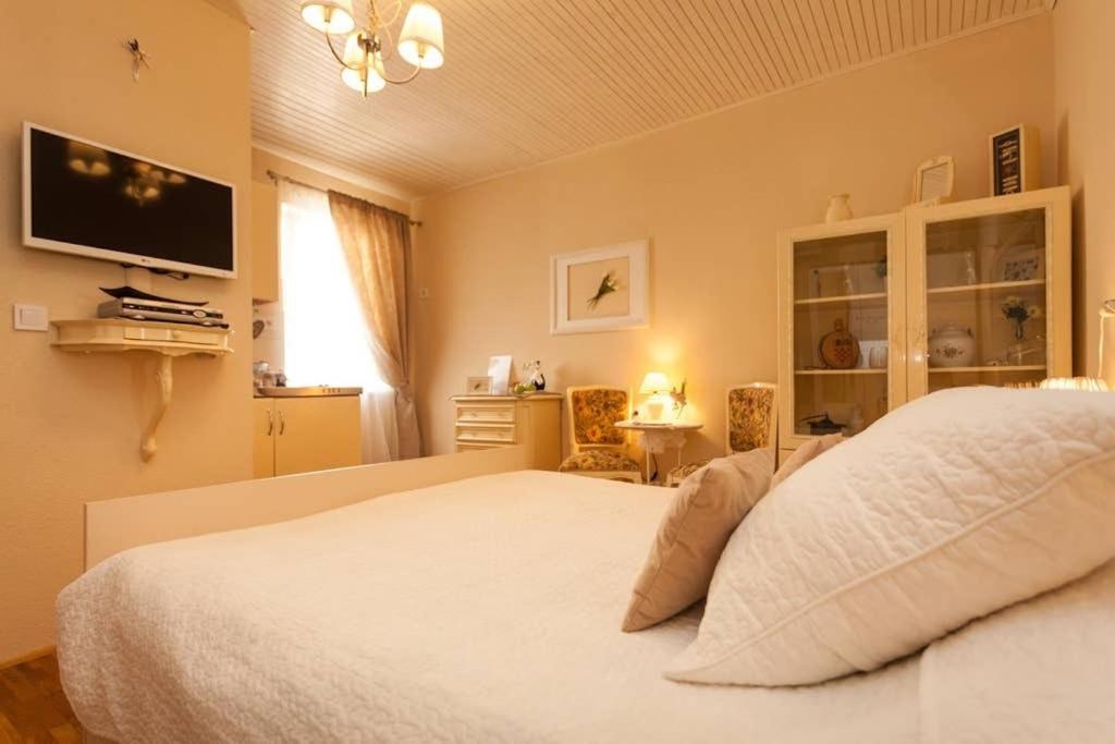 a bedroom with a white bed and a tv on the wall at Apartment City Center Amaryllis in Rovinj