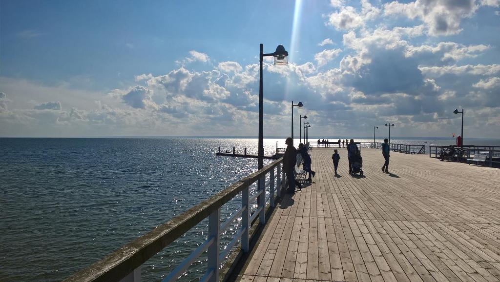 a group of people walking on a pier near the water at Apartament Jastarnia ul Bałtycka 26 in Jastarnia
