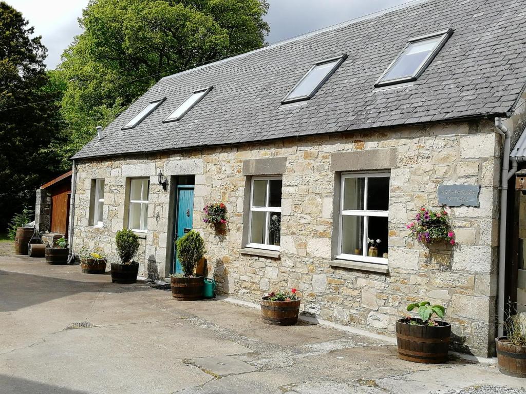 uma casa de pedra com vasos de plantas em frente em Ard Darach Cottage em Pitlochry
