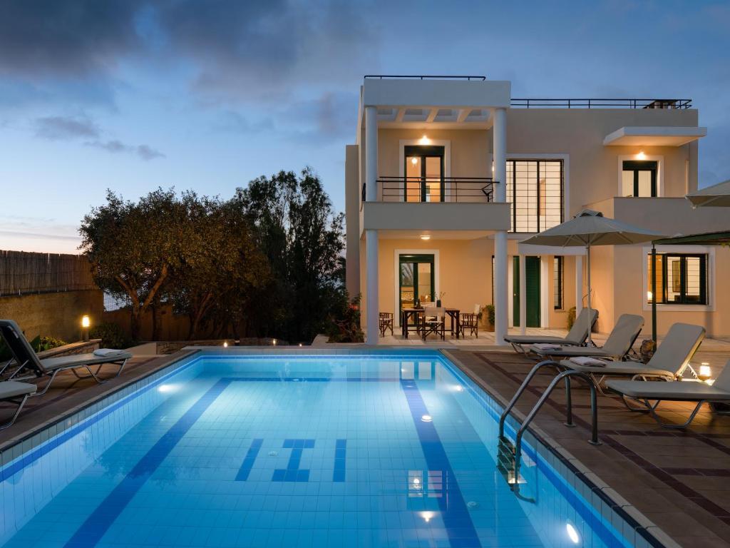 a villa with a swimming pool in front of a house at Aris Villa in Panormos Rethymno