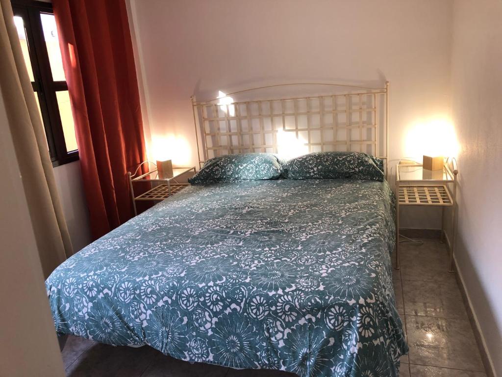 ein Schlafzimmer mit einem Bett mit blauer Decke und 2 Lampen in der Unterkunft APARTAMENTO GUAJARA in La Laguna