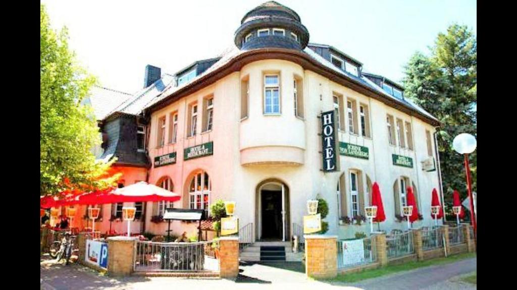 a large building with a cafe in front of it at Hotel & Restaurant Schenk von Landsberg in Teupitz